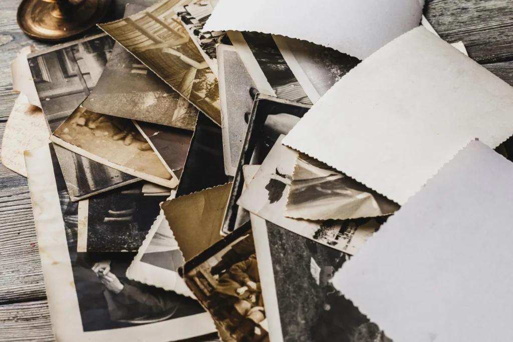 Fotografie di famiglia disposte su un tavolo, alcune girate sul retro, accanto a una scatola di ricordi.